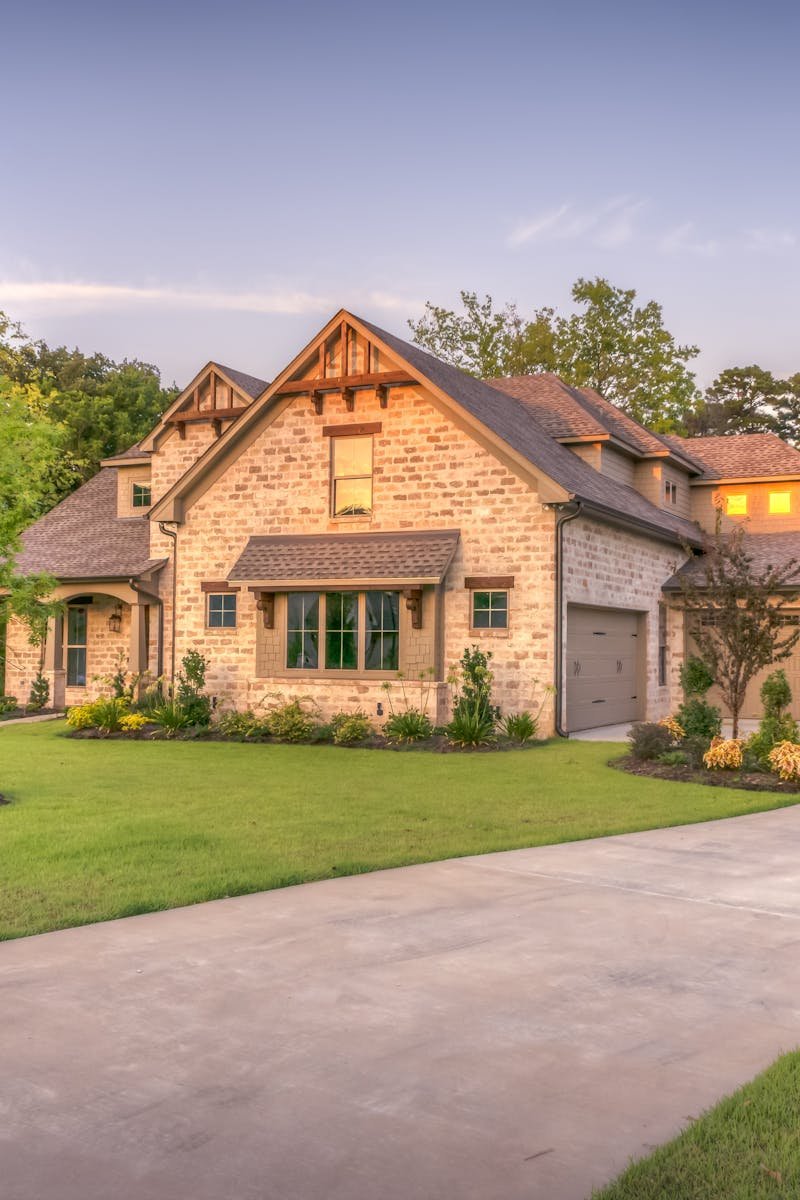 Elegant stone family home surrounded by trees, lush lawn, and vibrant garden.