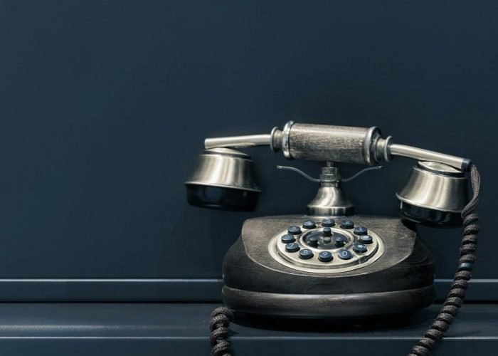 black and brown rotary phone near gray wall